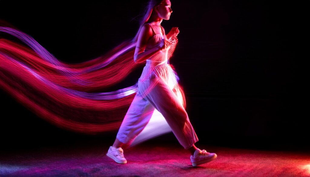 A young person walking surrounded by neon lights. background is in tones of red and purple