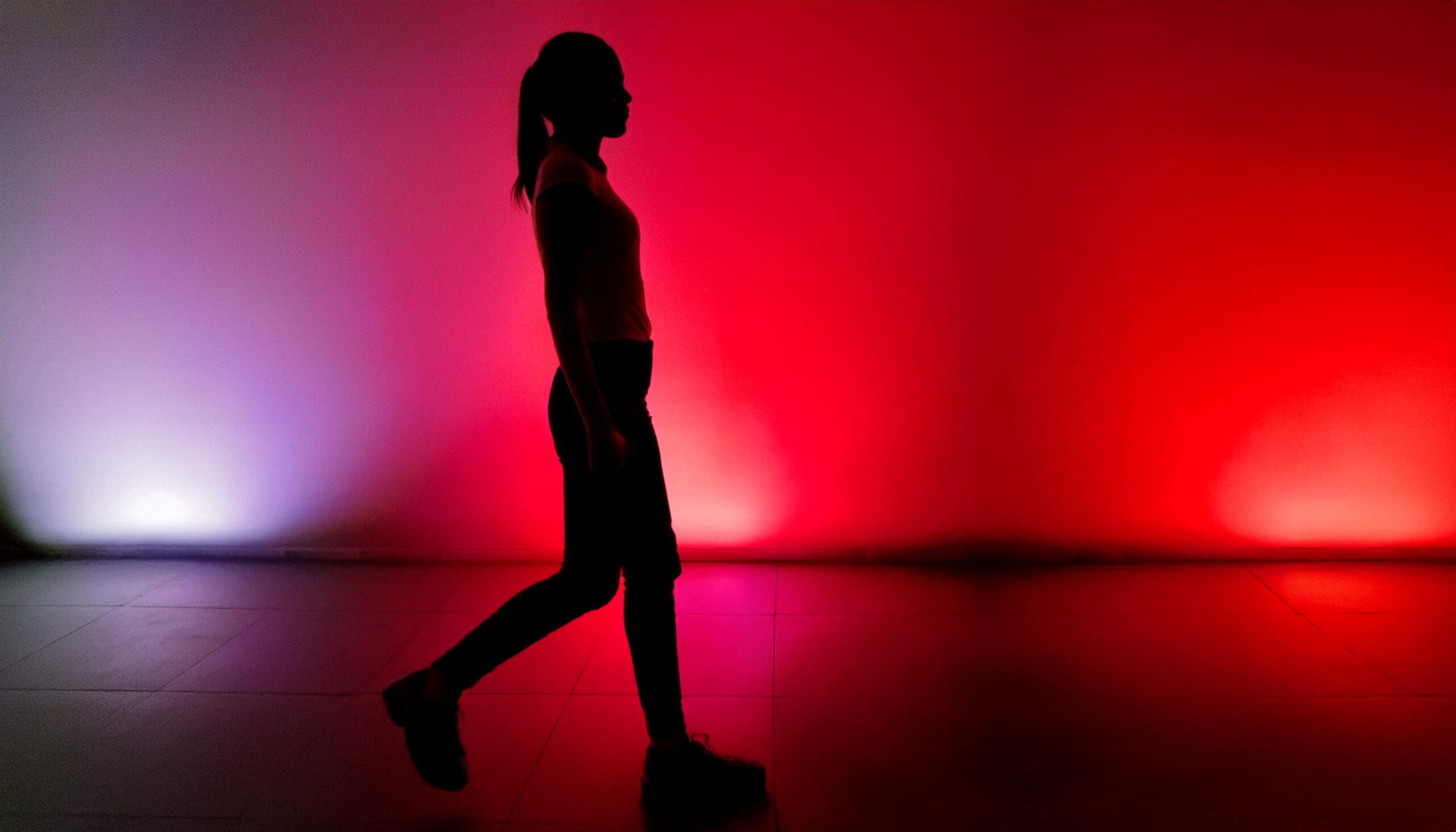 Silhouette of a woman walking surrounded by neon lights. background is in tones of red