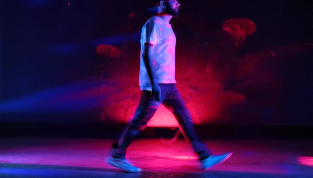 A young person walking surrounded by neon lights. background is in tones of red and purple