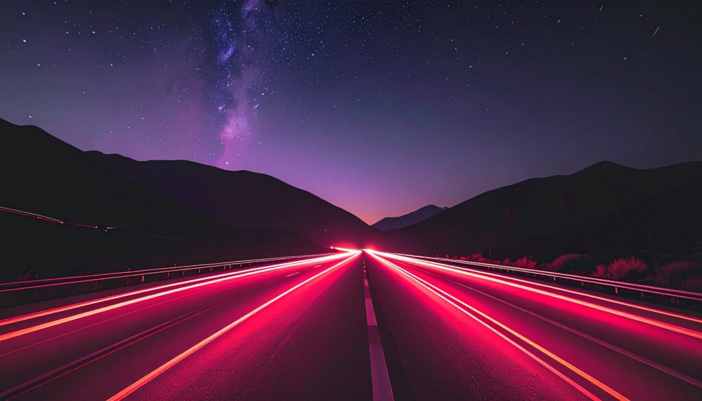 Long exposure traffic lights in the road at night. The sky is full of stars.